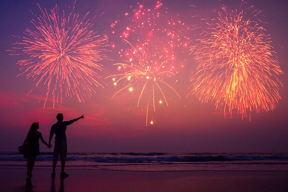 Two people watching fireworks on beach